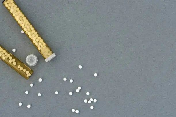 Vials spilling small white hormone pellets on a gray surface