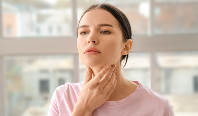 Woman holds her neck concerned about thyroid issues.